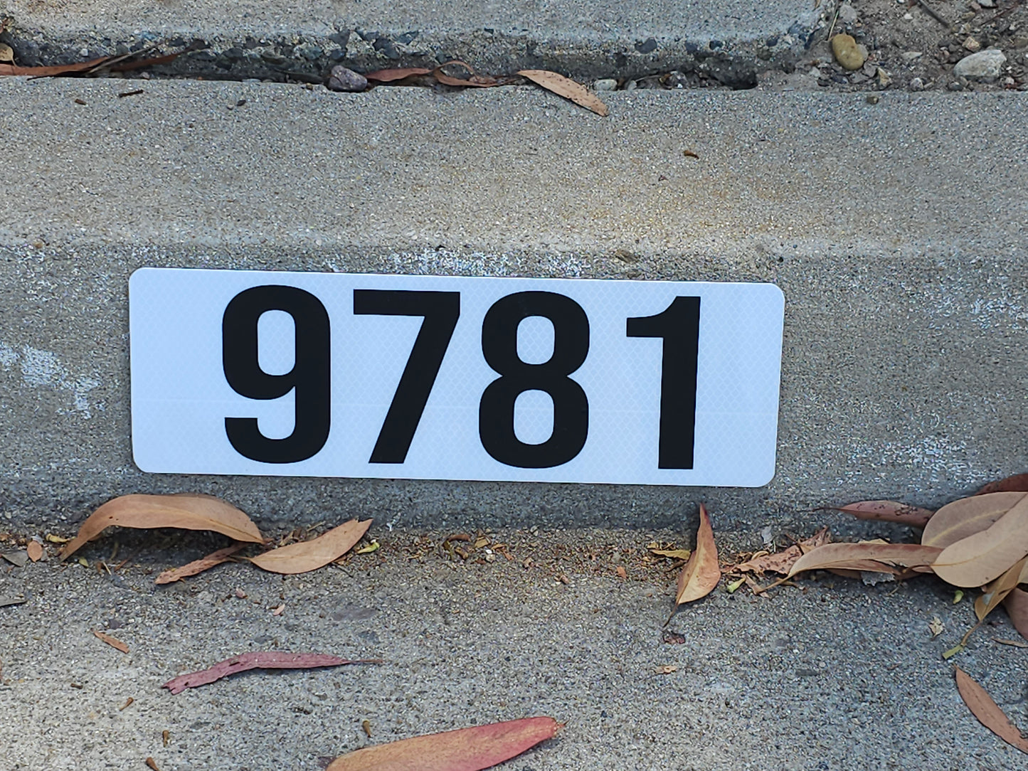 Reflective curb address sign by Address Appear fitting perfectly on residential curb with bold 4-inch black numbers